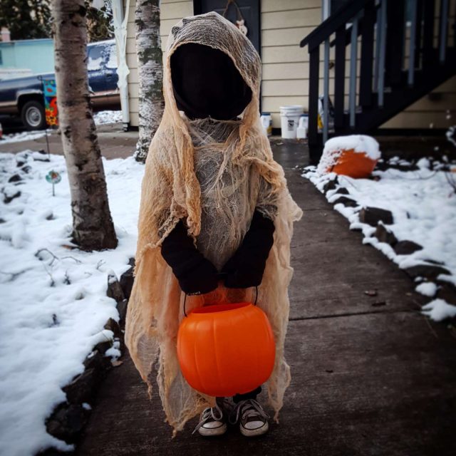 Child in a scary ghost costume with a haunted look, ready for Halloween trick-or-treating